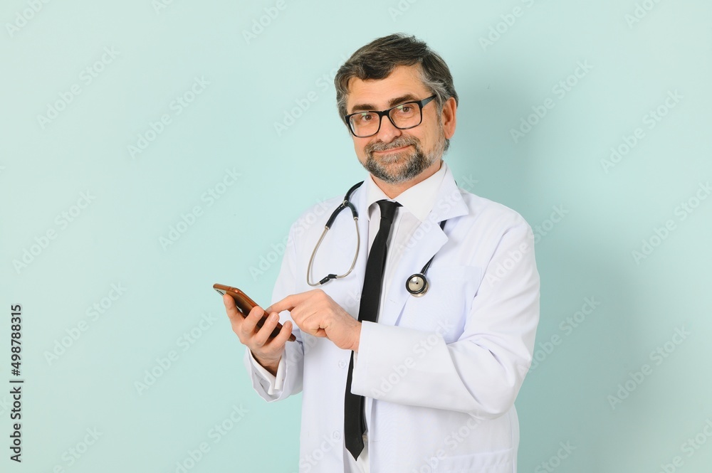 Senior doctor man wearing stethoscope and medical coat over blue background. Cheerful expression