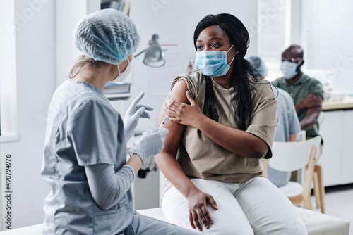 Foto African girl in mask consulting with nurse after being vaccinated during her vis
