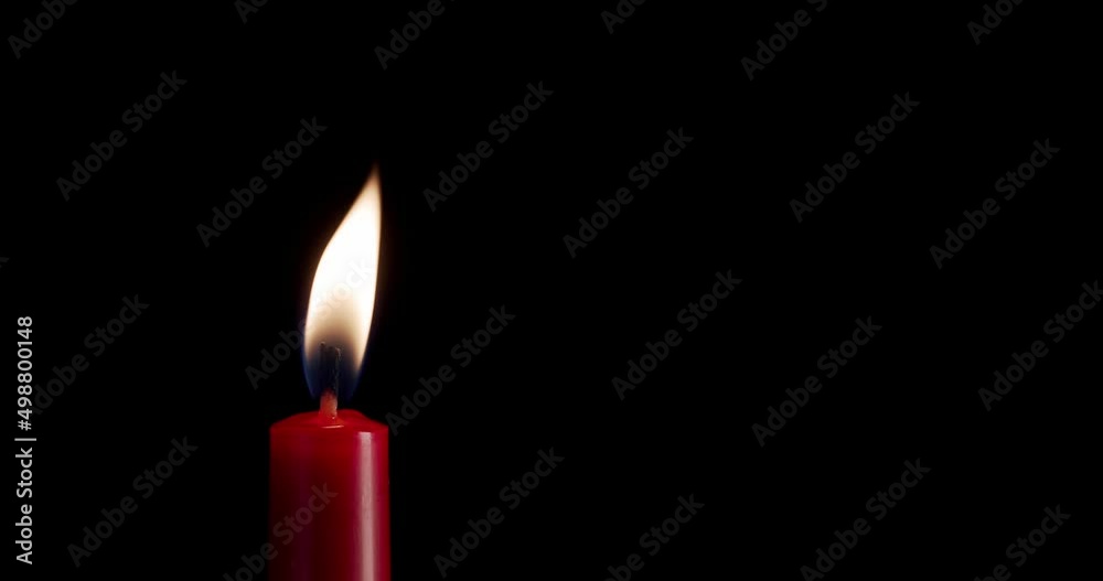 A single white candle burning.Isolated candle burning with dark background.White paraffin candle with yellow shades burns on a black background.Background or illustration of remembrance or celebration A single white candle burning.Isolated candle burning with dark background.White paraffin candle with yellow shades burns on a black background.Background or illustration of remembrance or celebration