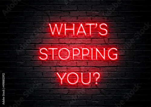 Red neon sign motivational quote with brick wall background. What's stopping you. 