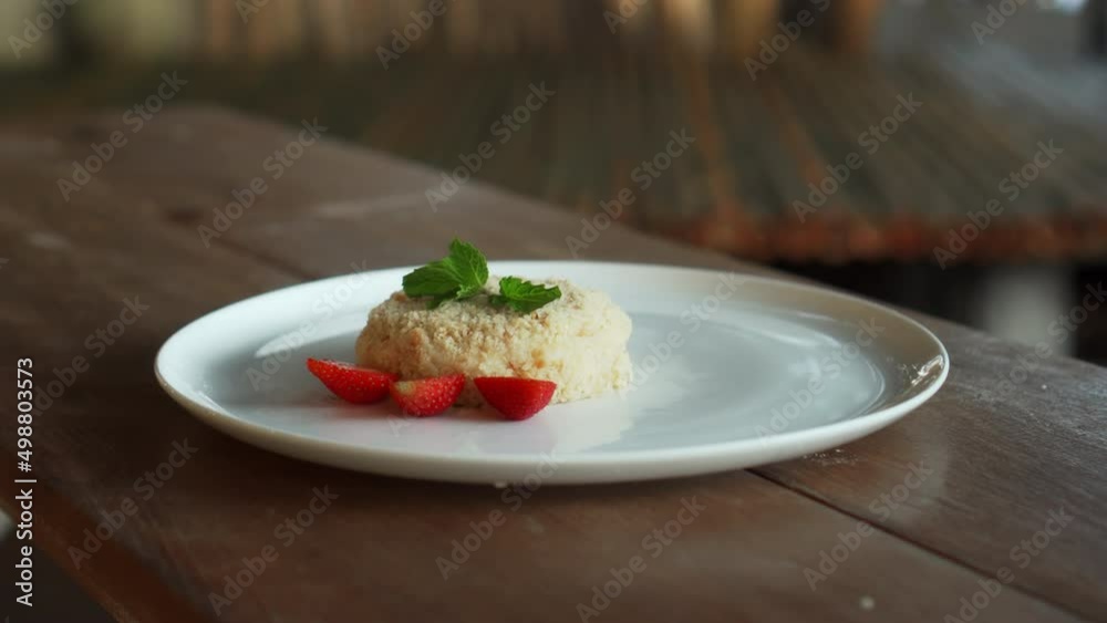 Little napoleon cake with strawberries on top standing on a white plate Little napoleon cake with strawberries on top standing on a white plate