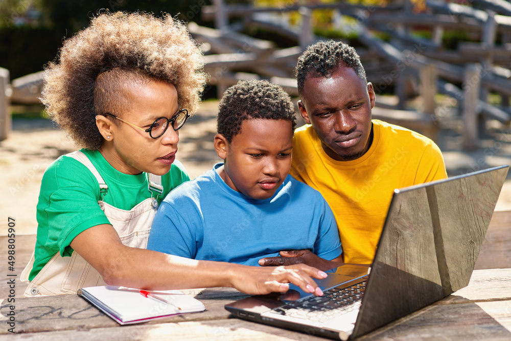 Beautiful young Afro American parents and cute little son are using a laptop Beautiful young Afro American parents and cute little son are using a laptop