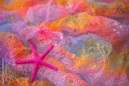 Knit surface of beachwear in rainbow color with starfish. Close-up of soft multicolored knitted patterns texture as background. Sea vacation  beach season.