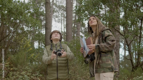 Beautiful woman and her son exploring wildlife and birdwatching in natural park on autumn day. Curious boy taking photo of birds, then showing picture to his mother. Nature, discovery concept