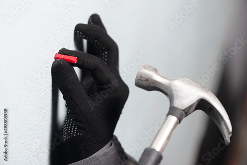 Worker inserts a plastic dowel into the wall close up. photo