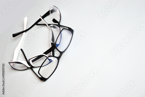 Glasses in a black and white frame, randomly lying on a white background. Accessories for vision correction. Optics.