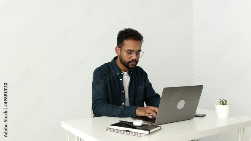 Young african freelancer man in glasses working on laptop at home. Casual concentrated entrepreneur developing new project while working on computer at home. Young african freelancer man in glasses working on laptop at home. Casual concentrated entrepreneur developing new project while working on computer at home.