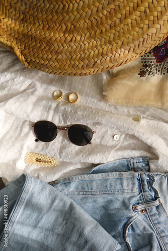Mom jeans, white blouse, boho scarf, wicker bag, sunglasses, gold rings and pearl accessories. Flat lay. 