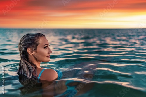 A girl with beautiful facial features looks into an unknown distance while sitting in the estuary