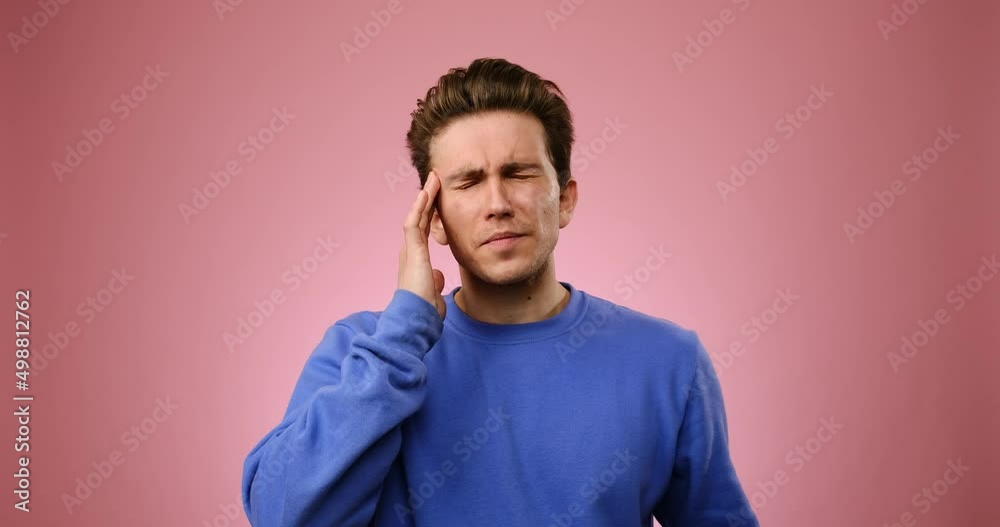 Man suffering from severe headache over pink background Man suffering from severe headache over pink background