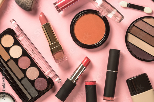 Make up products at pink background. Eye shadow, powder, cream, lipstick and more for professional make up. Flat lay image.