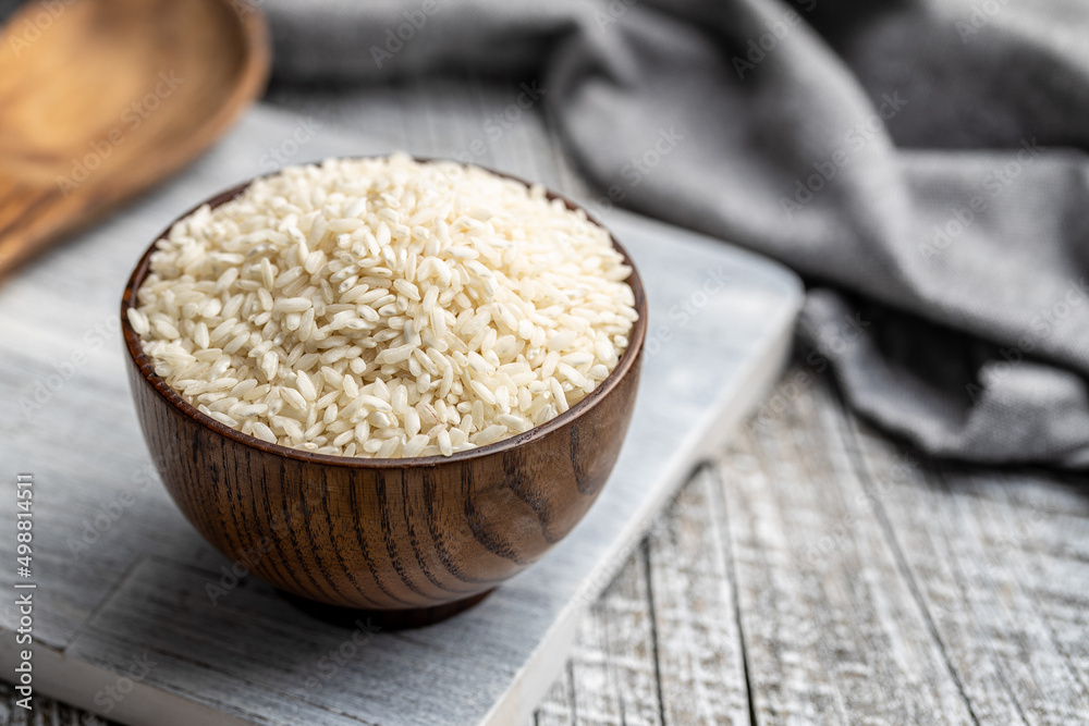 Uncooked Carnaroli risotto rice in bowl on wooden table. Uncooked Carnaroli risotto rice in bowl on wooden table.