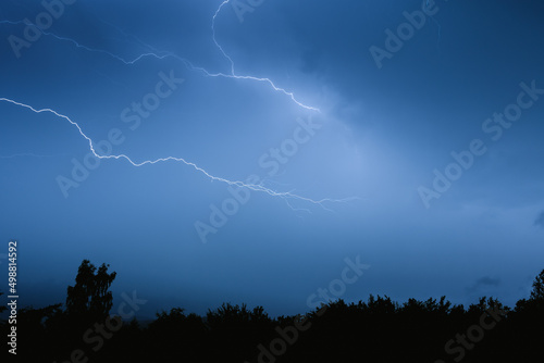 Electrical discharges during a summer storm, branched lightning bolts in the night sky.