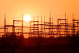Power lines, high masts for electricity transmission, view at sunset with the sun.