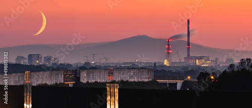 Evening panorama of Wroclaw at sunset with waxing crescent, Sobotka mountain in the background, view from the city ring road. photo