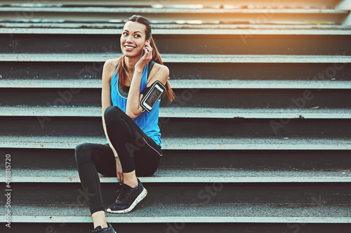 Amp up your workout. Shot of a sporty young woman listening to music while sitting on a staircase.