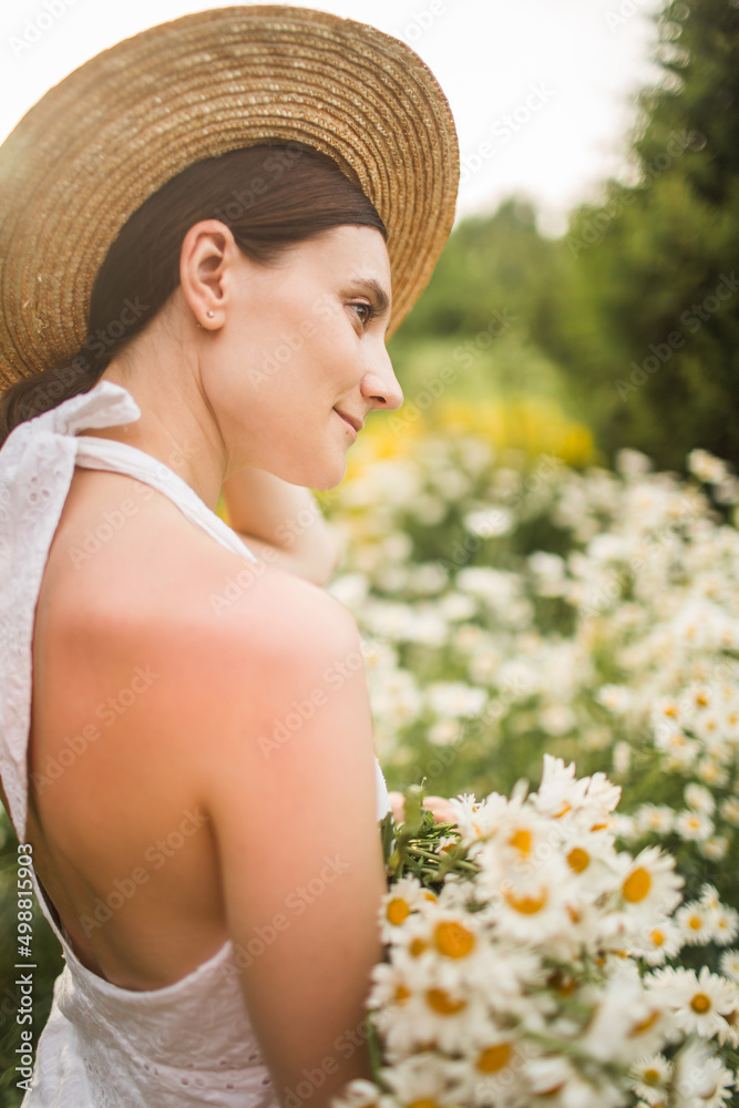 beautiful woman in a hat with a large bouquet of daisies