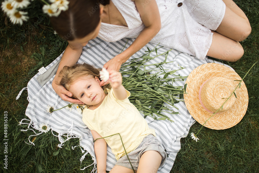 mother plays with her daughter, relax, collect daisies