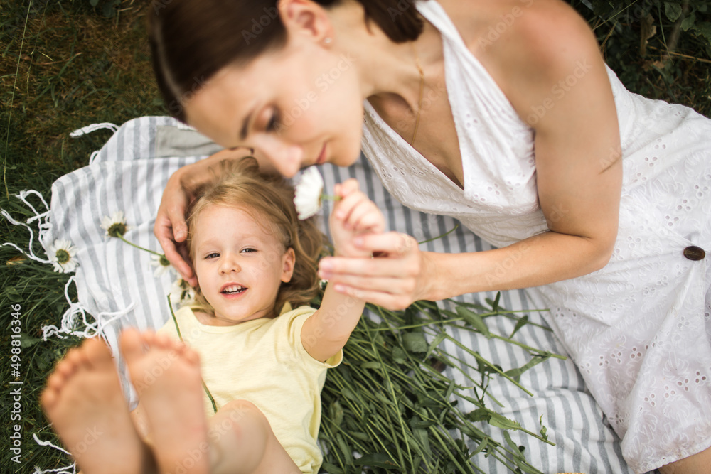 mother plays with her daughter, relax, collect daisies
