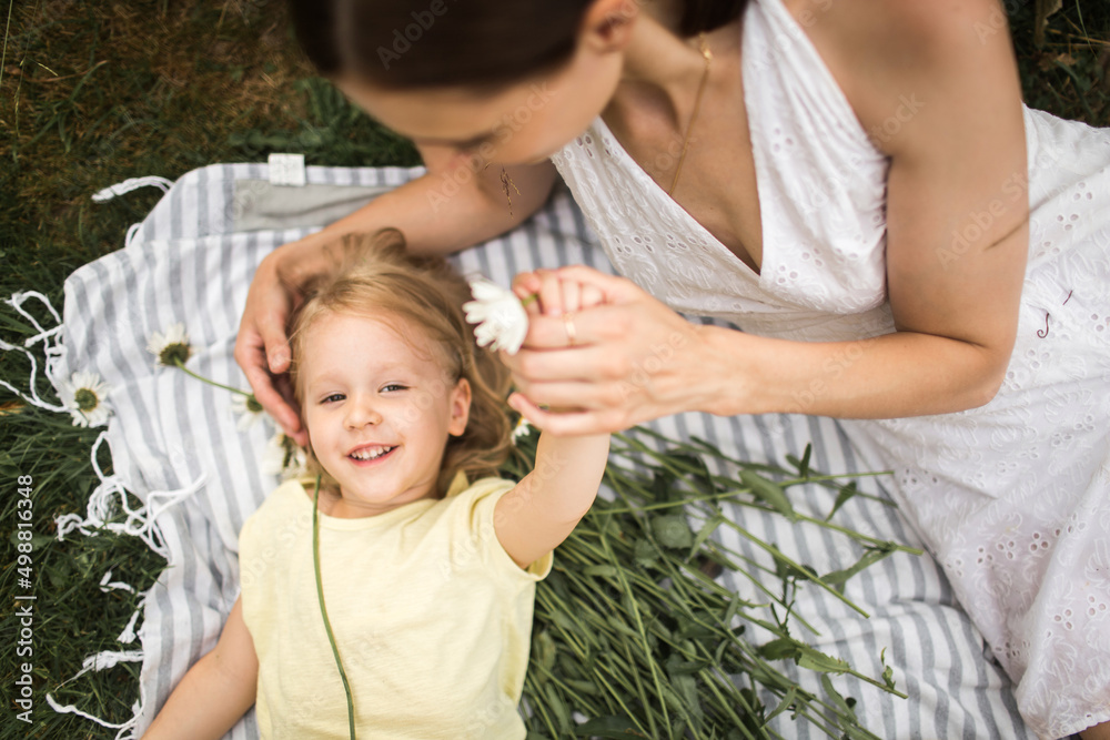 mother plays with her daughter, relax, collect daisies