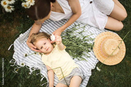 Obraz na płótnie mother plays with her daughter, relax, collect daisies w salonie