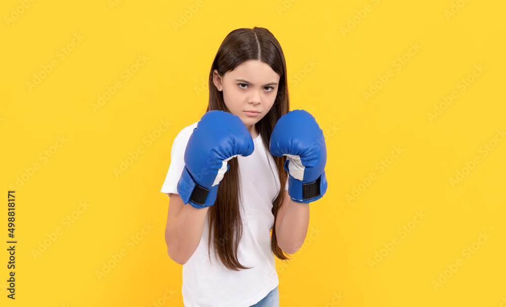 angry child punching in boxing gloves on yellow background