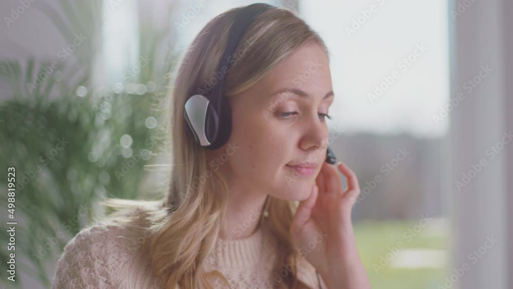 A beautiful call center operator Woman is sitting at desk while wearing headset communicating with customers