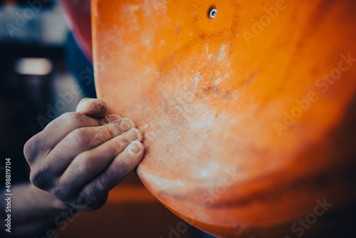 Male hand smeared with magnesium powder grabbing a hold of a climbing wall