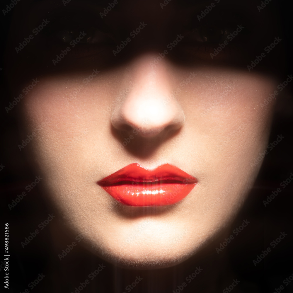 Obraz premium Beauty, fashion, make-up concept. Part of woman face hides in black shadow. Visible red sexy sparkling lips, nose and cheeks. Lips is in camera focus