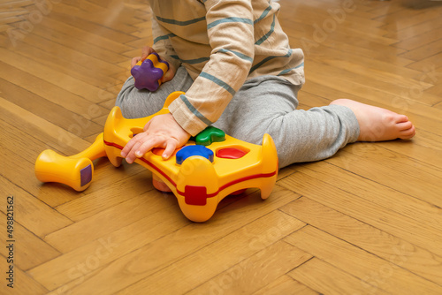 Cute little caucasian boy playing, collects multi-colored sorter constructor. Baby's hands puzzle sorter of plastic toy. Children logic development, childhood daycare education,kindergarten concept