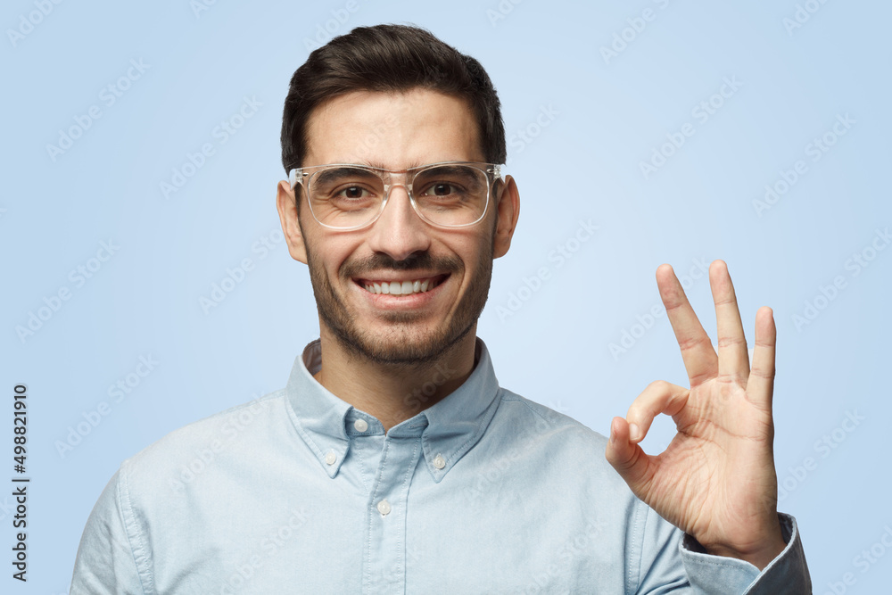 Young attractive man has happy look smiling, gesturing, showing OK gesture Young attractive man has happy look smiling, gesturing, showing OK gesture