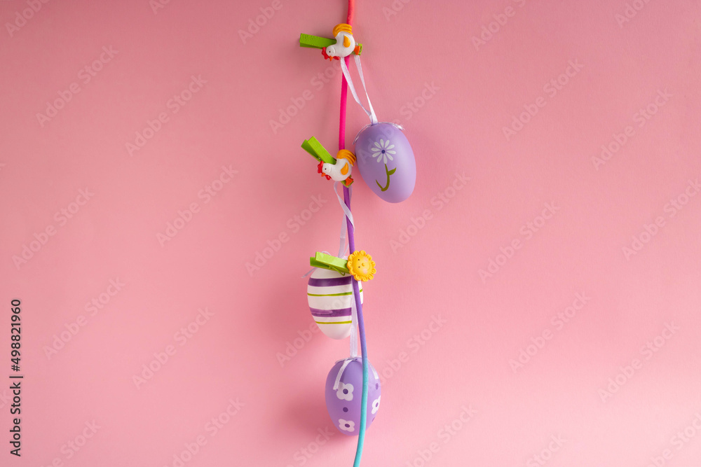 Fototapeta premium Easter lilac eggs on clothespins on a pink background. Easter concept.