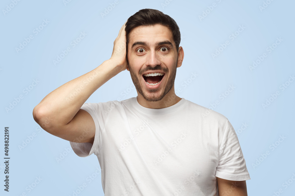 Handsome attractive surprised man looks at the camera astonished with big sale prices Handsome attractive surprised man looks at the camera astonished with big sale prices