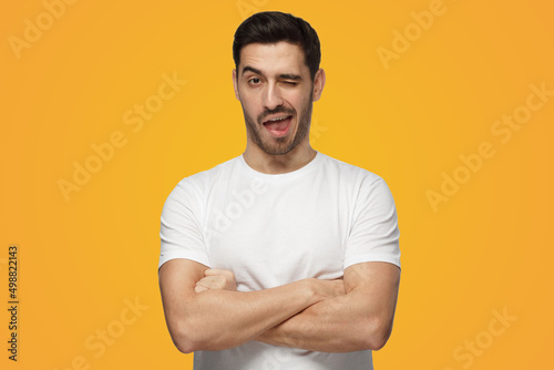 Young man winking friendly as if inviting to adventure or recommending good benefit photo