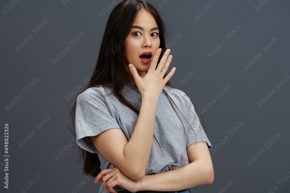 portrait woman with long hair in a gray T-shirt gesturing with hands Gray background