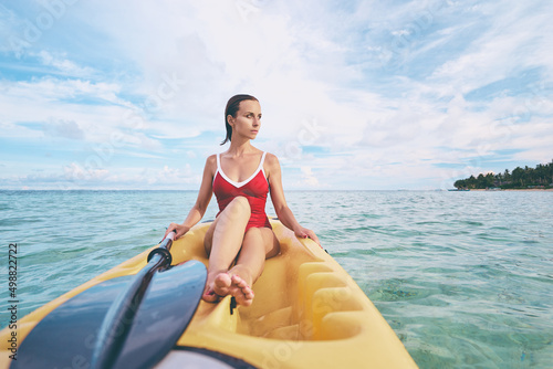 Young woman paddling the sea kayak in thel calm lagoon.