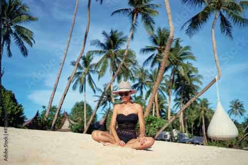 Vacation on the seashore.Young woman in hat and swimsuit on the beautiful tropical white sand beach resort. © luengo_ua