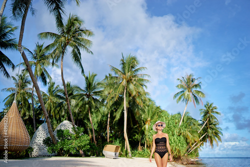 Vacation on the seashore.Young woman walking on the beautiful tropical white sand beach resort. © luengo_ua