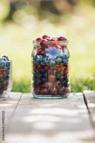 Glassware with different fresh berries on an old wooden bench. Fresh garden berries, blueberry,currant, cherry