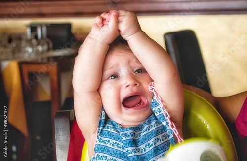 Young child throwing a tantrum in her high chair in a restaurant photo