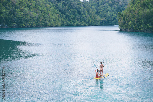 Summer holidays vacation travel. SUP Stand up paddle board. Young women sailing together on beautiful calm lagoon. © luengo_ua