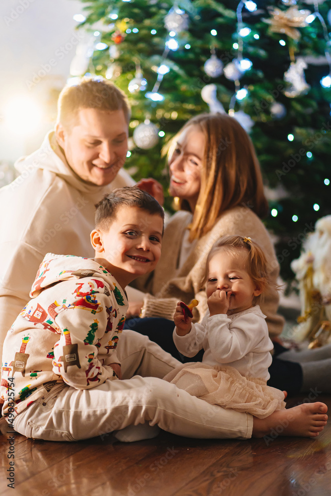 a happy family with two small children at home by the Christmas tree. a happy family with two small children at home by the Christmas tree.