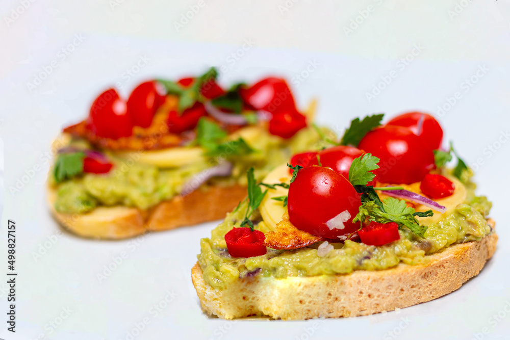 Healthy open vegan sandwich with avocado mash, zucchini, cherry tomatoes, cheese on top of corn bread. Healthy food, vegetarian food concept