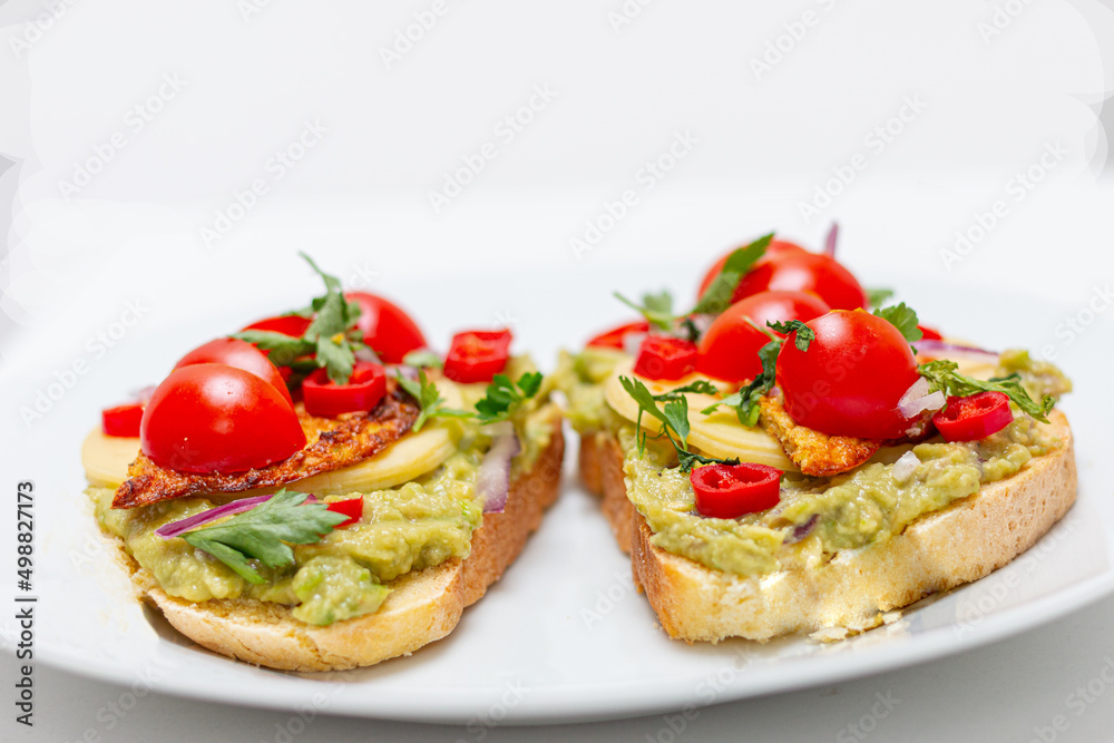 Healthy open vegan sandwich with avocado mash, zucchini, cherry tomatoes, cheese on top of corn bread. Healthy food, vegetarian food concept Healthy open vegan sandwich with avocado mash, zucchini, cherry tomatoes, cheese on top of corn bread. Healthy food, vegetarian food concept