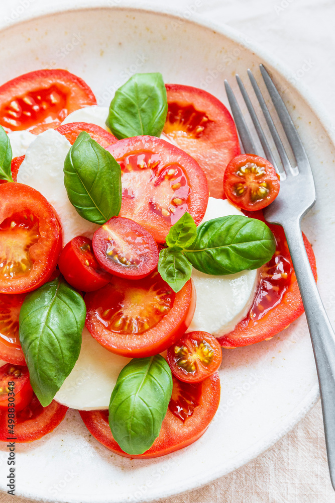 Tomato, mozzarella and basil salad in a ceramic bowl, with fork. Tomato, mozzarella and basil salad in a ceramic bowl, with fork.