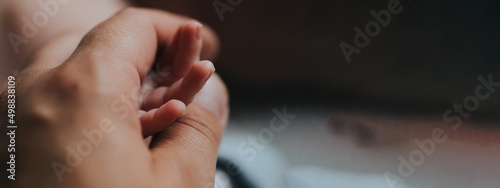 Fotografia Hand of sleeping baby in the hand of mother close-up on the bed , New family and