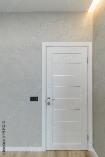 Classic white wooden door on a background of decorative plaster wall.
