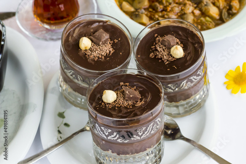 Cocoa pudding dessert layered with biscuits in staylish glasses on Ramadan Table.Garnished with nut and chocolate. photo