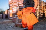 Close up on hands and midsection of unknown man construction worker taking orange hollow clay blocks ar warehouse or construction site in sunny summer day copy space