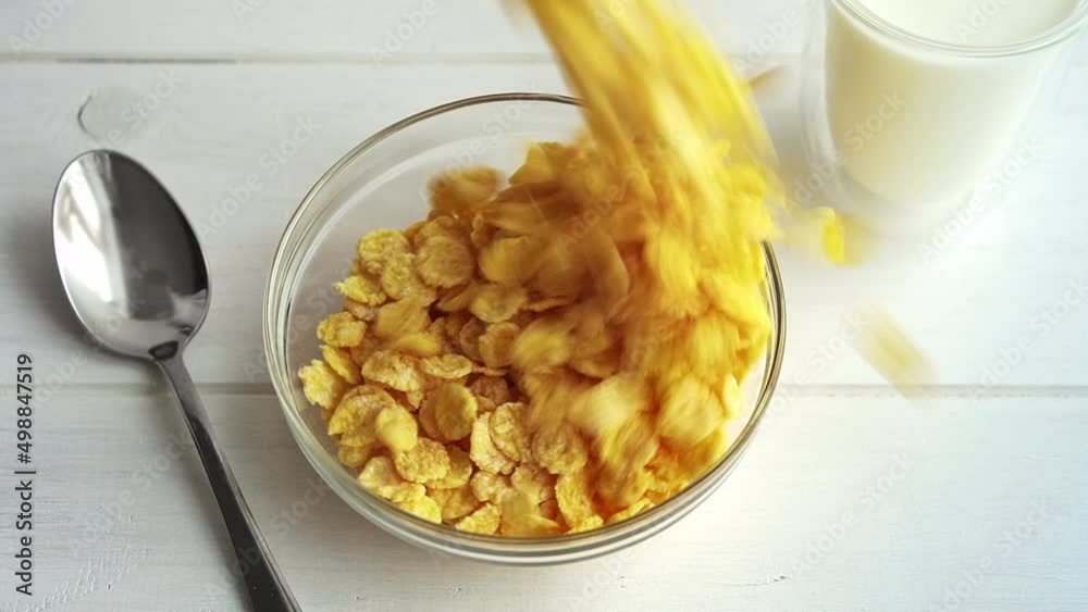 Corn flakes are poured into glass bowl on wooden table. Corn flakes and milk healthy breakfast concept Corn flakes are poured into glass bowl on wooden table. Corn flakes and milk healthy breakfast concept